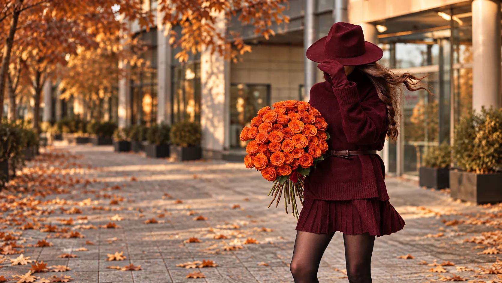 Woman in a burgundy hat holding a bouquet of orange roses